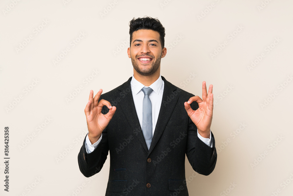 Young handsome businessman man over isolated background showing an ok sign with fingers Young handsome businessman man over isolated background showing an ok sign with fingers
