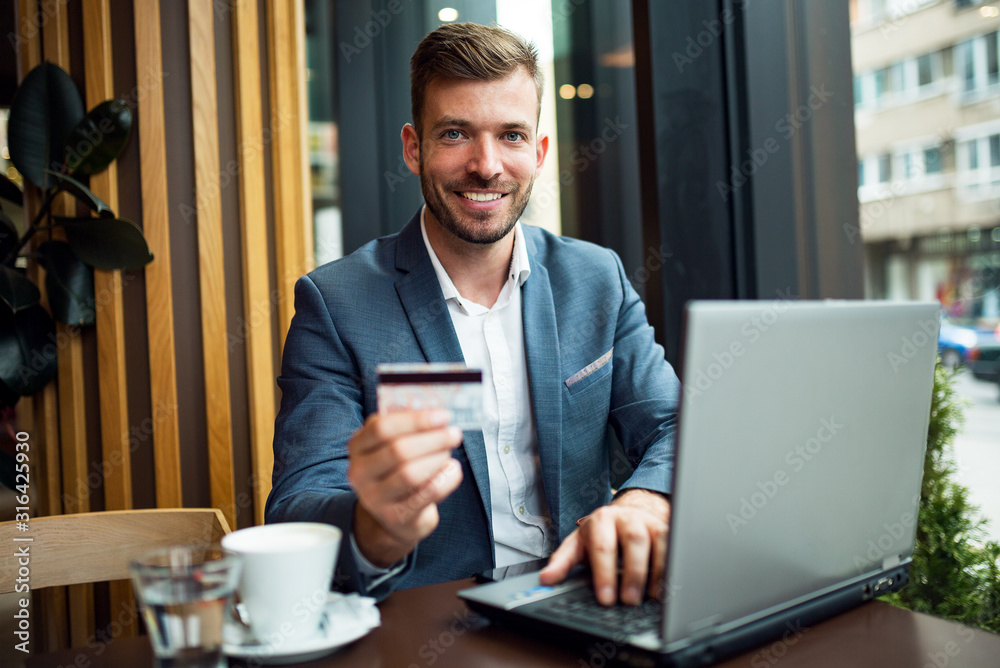 Smiling businessman using laptop and credit card Smiling businessman using laptop and credit card