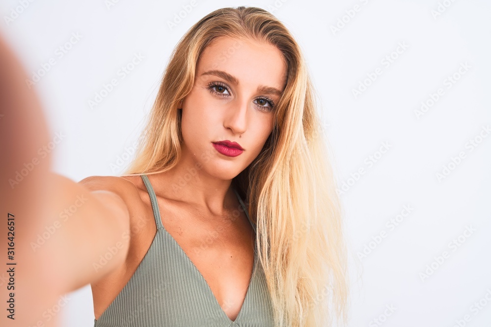 Young beautiful woman wearing t-shirt make selfie by camera over isolated white background with a confident expression on smart face thinking serious Young beautiful woman wearing t-shirt make selfie by camera over isolated white background with a confident expression on smart face thinking serious