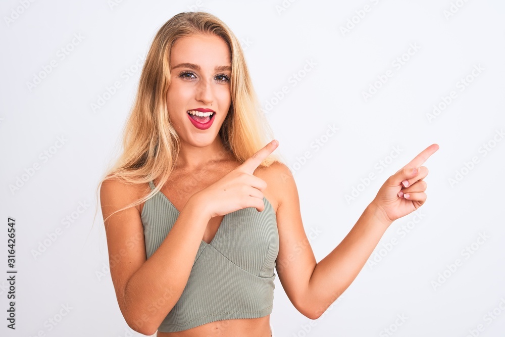 Young beautiful woman wearing casual green t-shirt standing over isolated white background smiling and looking at the camera pointing with two hands and fingers to the side. Young beautiful woman wearing casual green t-shirt standing over isolated white background smiling and looking at the camera pointing with two hands and fingers to the side.