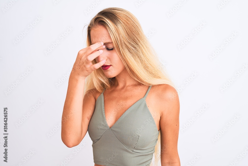 Young beautiful woman wearing casual green t-shirt standing over isolated white background tired rubbing nose and eyes feeling fatigue and headache. Stress and frustration concept. Young beautiful woman wearing casual green t-shirt standing over isolated white background tired rubbing nose and eyes feeling fatigue and headache. Stress and frustration concept.