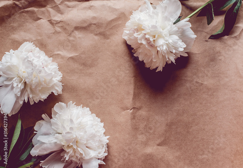 White peonies pattern on craft paper background with copy space, flat lay photo