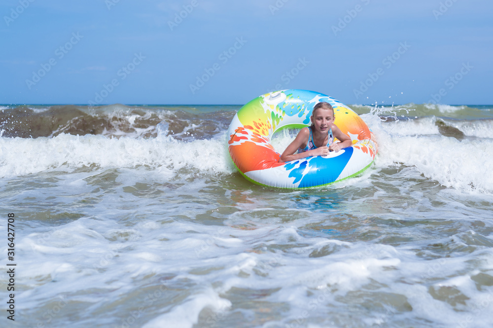 Obraz premium Girl on an inflatable circle in a raging sea, ocean.