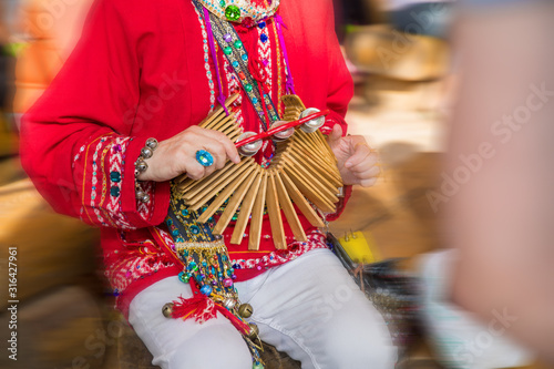 Male hands of a caucasian man, dressed in traditional attire, hold a wooden tap dance instrument.