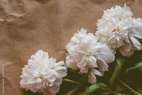 White peonies pattern on craft paper background with copy space, flat lay photo