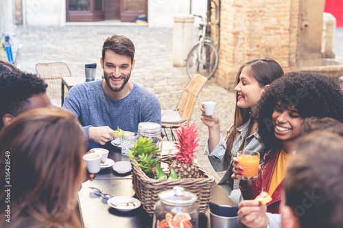 Fotografia Group of young multiracial people having breakfast in an outdoor coffee shop