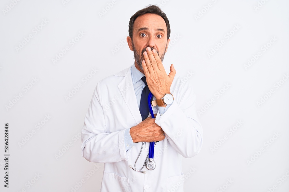 Middle age doctor man wearing coat holding stethoscope over isolated white background cover mouth with hand shocked with shame for mistake, expression of fear, scared in silence, secret concept Middle age doctor man wearing coat holding stethoscope over isolated white background cover mouth with hand shocked with shame for mistake, expression of fear, scared in silence, secret concept