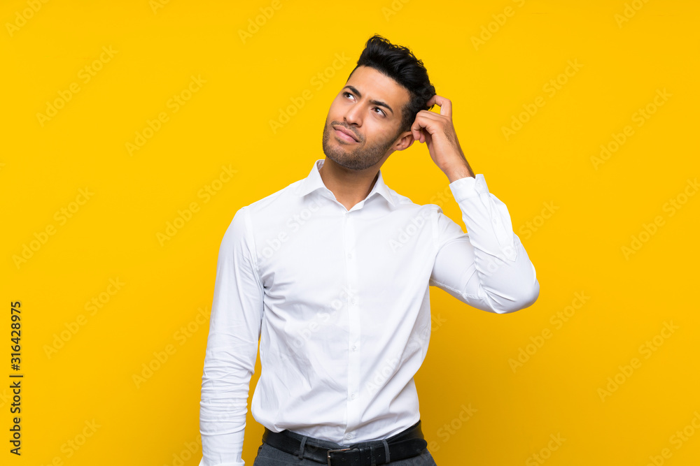 Young handsome man over isolated yellow background having doubts and with confuse face expression Young handsome man over isolated yellow background having doubts and with confuse face expression