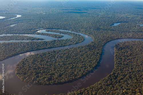 View of the Amazon River from an airplane, dense tropical forest, reflection in the water.