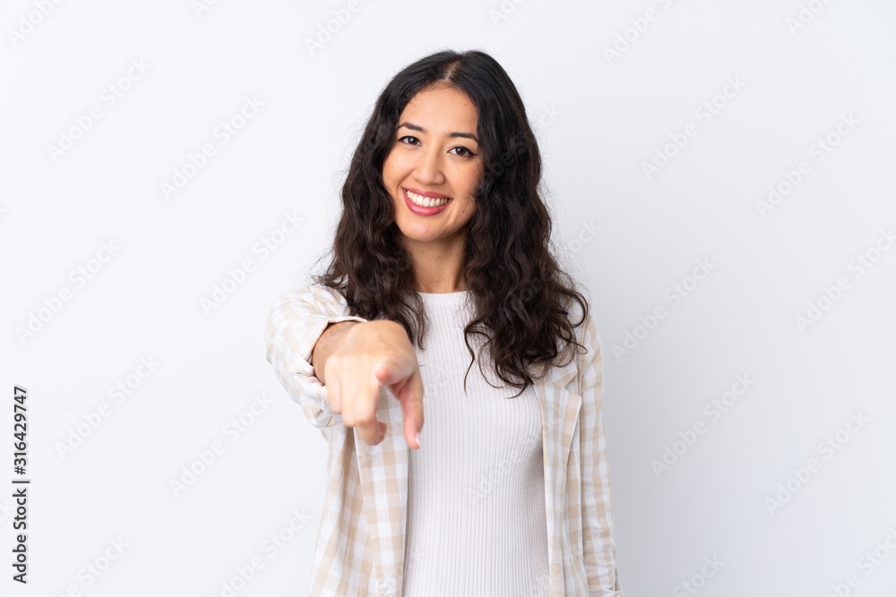 Mixed race woman over isolated white background points finger at you with a confident expression Mixed race woman over isolated white background points finger at you with a confident expression
