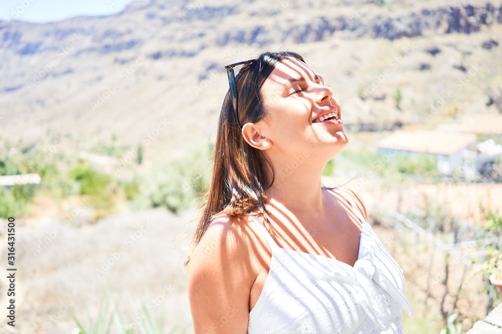 Young beautiful tourist woman smiling happy around mountain landscape enjoying summer vacation on a road trip Young beautiful tourist woman smiling happy around mountain landscape enjoying summer vacation on a road trip