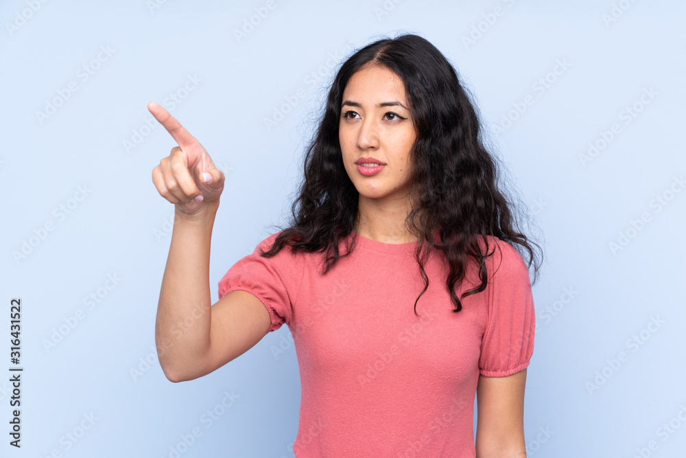Mixed race woman wearing a sweater over isolated blue background touching on transparent screen Mixed race woman wearing a sweater over isolated blue background touching on transparent screen