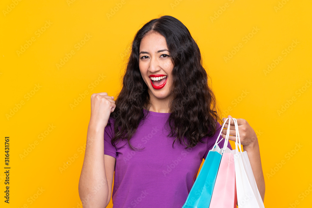 Spanish Chinese woman with shopping bag over isolated background celebrating a victory Spanish Chinese woman with shopping bag over isolated background celebrating a victory