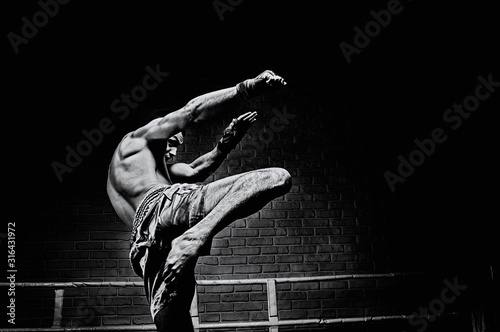 Canvas Print Thai boxer in the ring hits with a knee