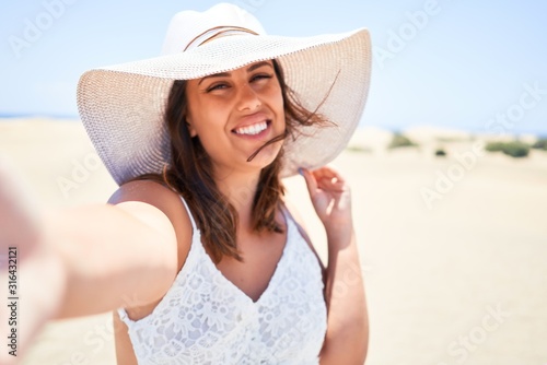 Young beautiful woman smiling happy taking a selfie using smartphone at maspalomas dunes beach