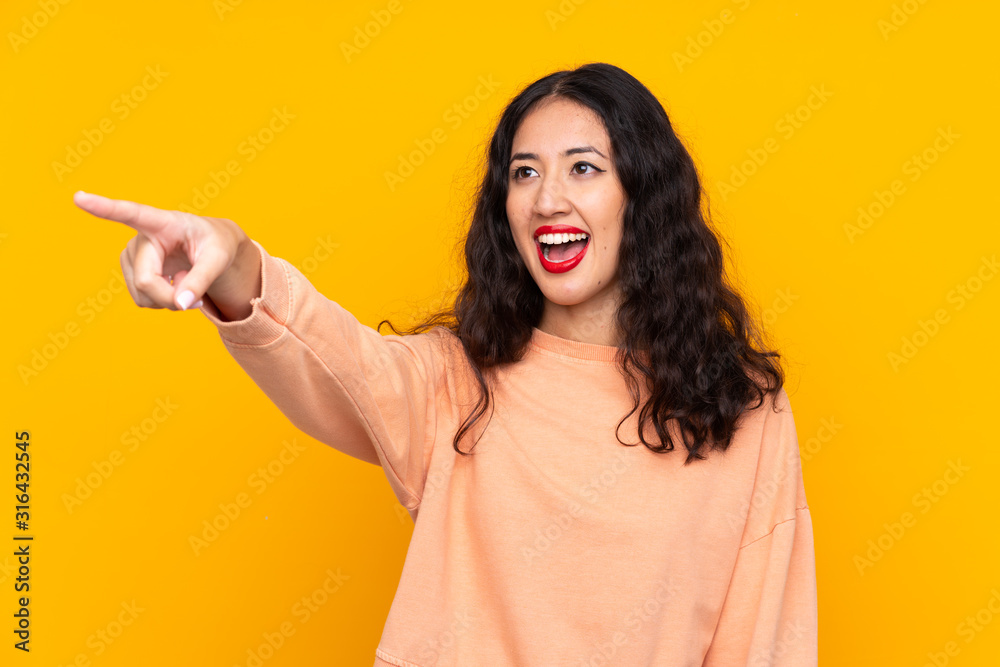 Spanish Chinese woman over isolated yellow background pointing away Spanish Chinese woman over isolated yellow background pointing away