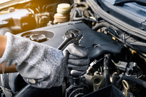 Auto mechanic working on car engine in mechanics garage. Repair service. authentic close-up shot © Chaiyuth