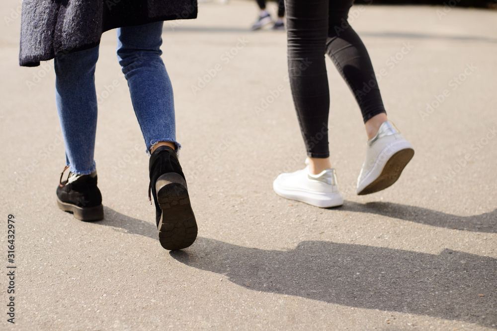Students are going to campus together in sunny day. Legs of female students going forward Students are going to campus together in sunny day. Legs of female students going forward