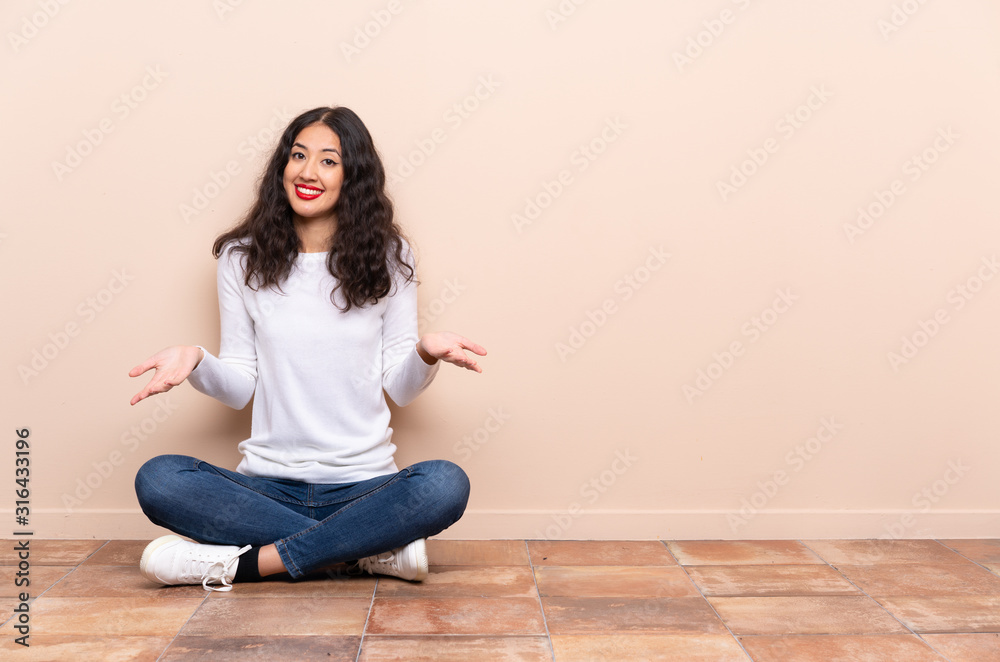Young woman sitting on the floor smiling - obrazy, fototapety, plakaty 