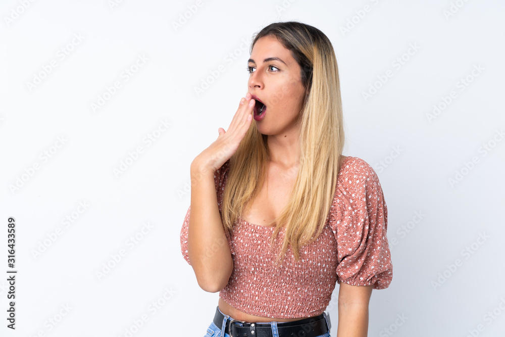 Young Uruguayan woman over isolated white background yawning and covering wide open mouth with hand Young Uruguayan woman over isolated white background yawning and covering wide open mouth with hand