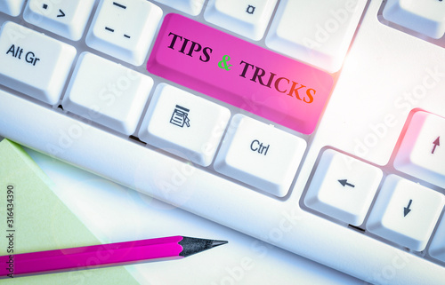 Writing note showing Tips And Tricks. Business concept for Steps Lifehacks Handy advice Recommendations Skills White pc keyboard with note paper above the white background photo