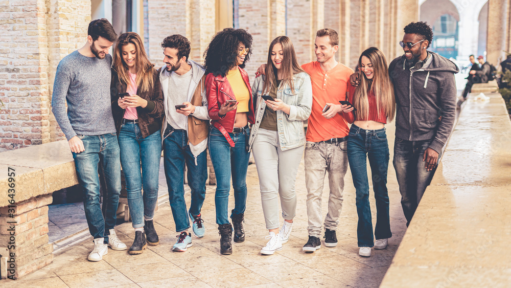 group of interracial friends meeting in the city center. they are having fun with smart phones and social media, walking together and chatting together. foto de Stock | Adobe Stock