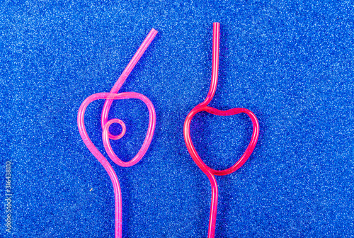 Heart shaped cocktail tubes on a blue background.