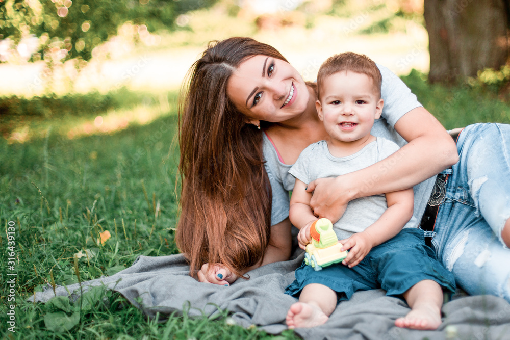 Mother with little son spend time together in green park. Mother with little son spend time together in green park.