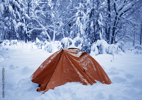 Camping tent on snow in snowy winter forest after snowfall