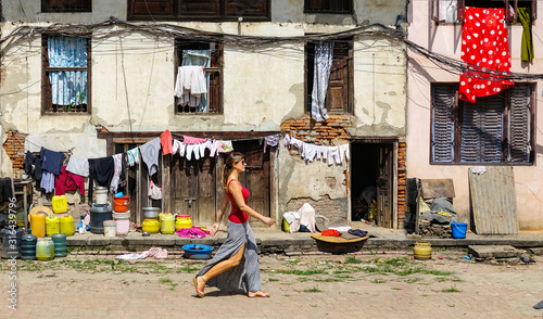 Принти на полотні Woman walks past an old deteriorating house in residential part of Kathmandu