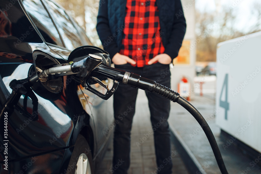 Man with gun fuels vehicle on gas station Man with gun fuels vehicle on gas station