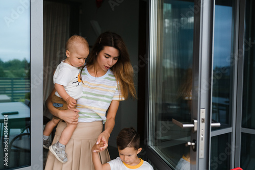 Young mother playing and having fun with her baby boy son brothers in a green garden with cars - Family values warm color summer scene - Eastern European Latvia Riga