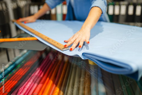 Woman measures the fabric in textile store photo