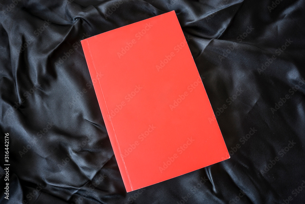 Red book on black background. Relaxation mood, cultural activity. Freedom, information, knowledge concept. Empty book cover for advertisement image montage.         - obrazy, fototapety, plakaty 