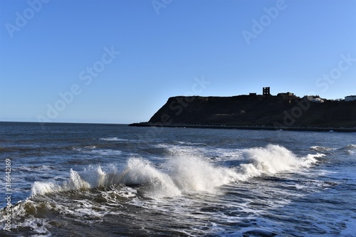 Waves crashing with a castle on the headland in the background