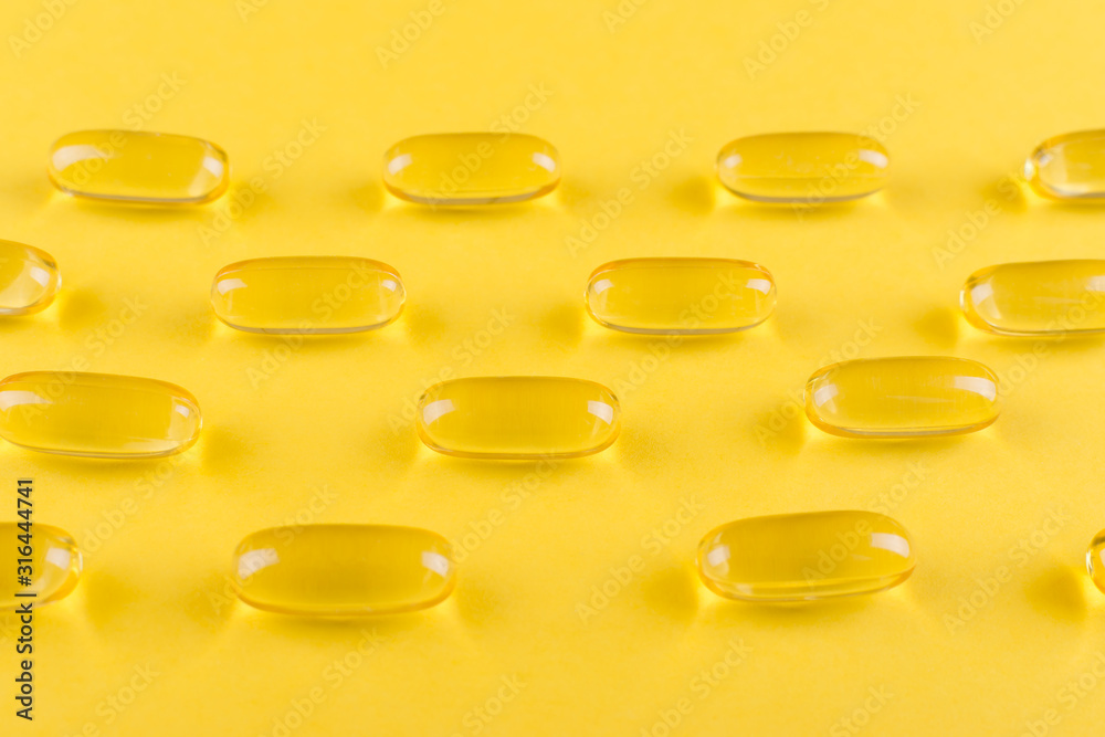 golden omega capsules on yellow background closeup golden omega capsules on yellow background closeup