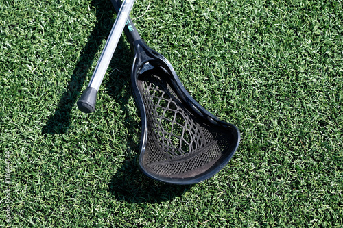 Various styles and colors of Lacrosse sticks on artificial turf during a womans Lacrosse tournament