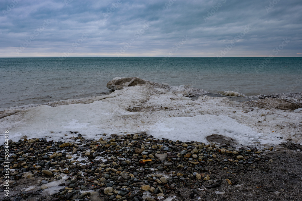 Ice floe buildup along the rocky shoreline of Lake Michigan on the United States side on a cloudy cold winter day