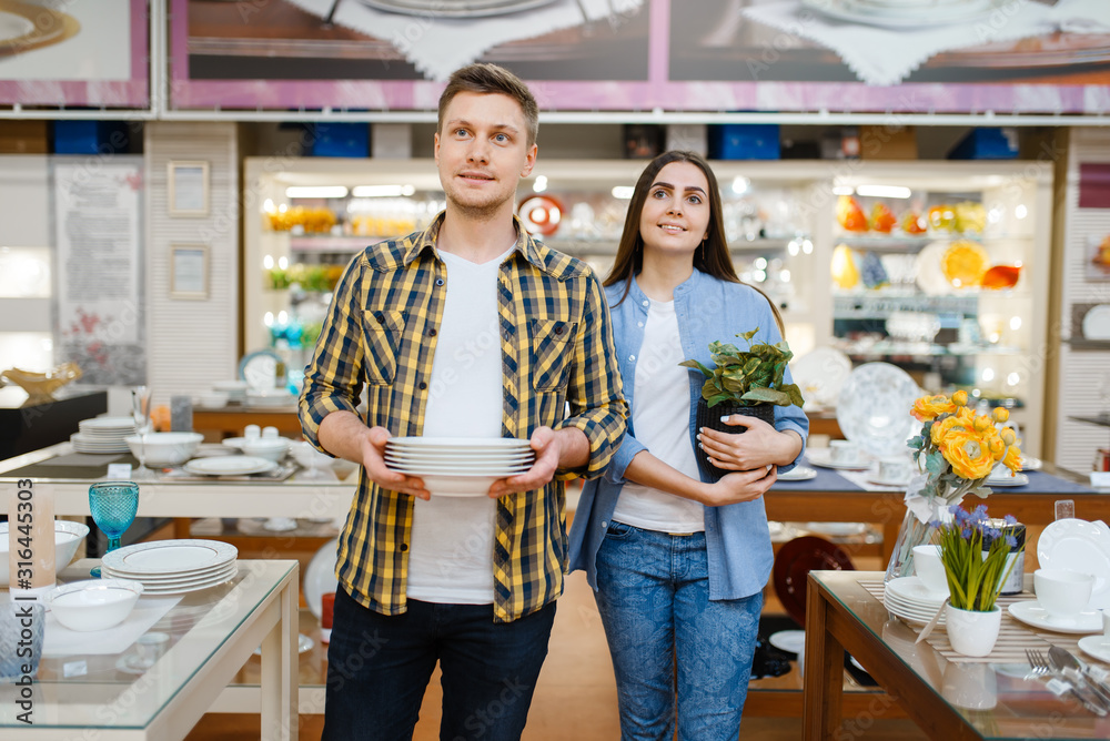 Young couple with plates in houseware store