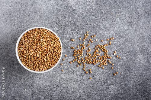 green buckwheat in a white plate on a grey background top view photo