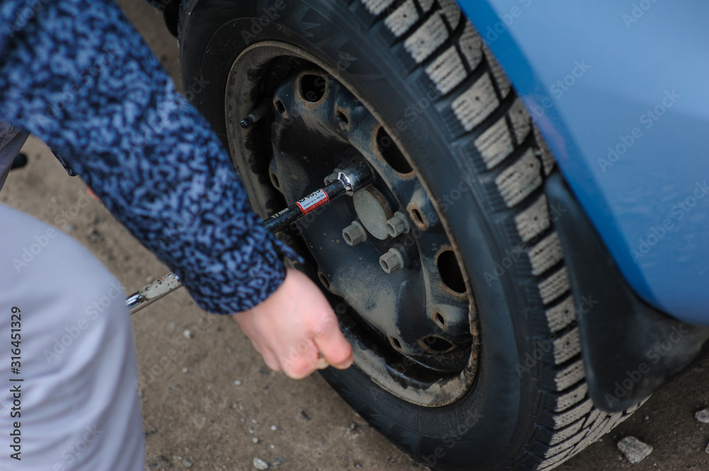 Man is changing tire with wheel on the car