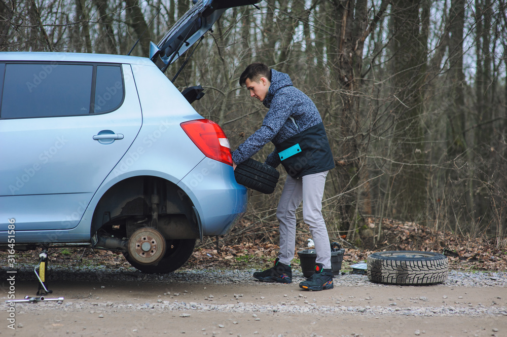 Man is changing tire with wheel on the car Man is changing tire with wheel on the car