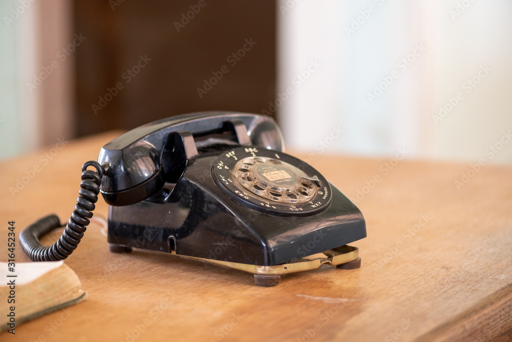 Old rotary phone, black, on wooden table, with copy space