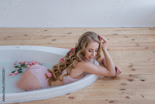 Fotografie A beautiful girl with long hair is basking in a fragrant bath
