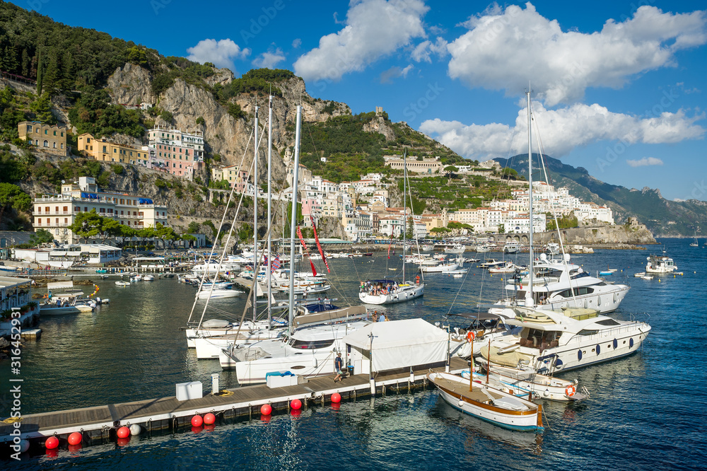 Sailing yachts and catamarans at Amalfi port. Sailing cruise route spot in Italy.