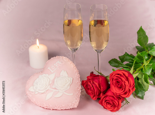 Valentine's day card, two glasses of champagne on a pink background red roses and a pink heart, a lit candle