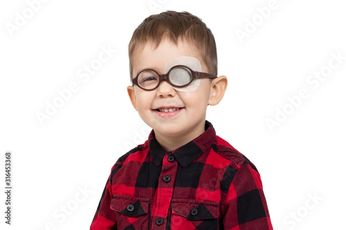 A little boy wears glasses and an eye patch  plaster  occluder  undergoes a hardware vision treatment to prevent amblyopia and strabismus  squint  lazy eye . Child congenital vision disease. Isolated.