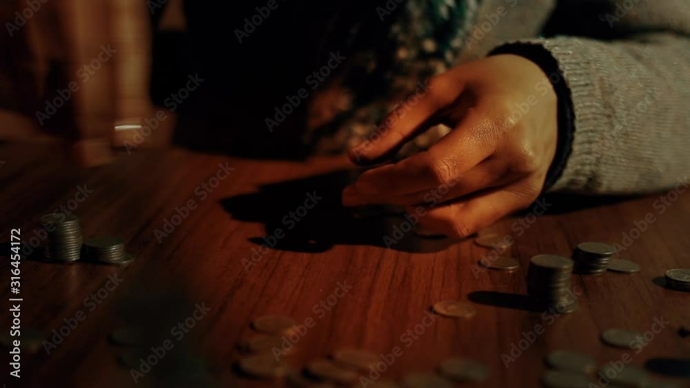 An elderly man counts coins on the table. A candle is burning. The concept of poverty and helplessness. Close - up of the room. An elderly man counts coins on the table. A candle is burning. The concept of poverty and helplessness. Close - up of the room.