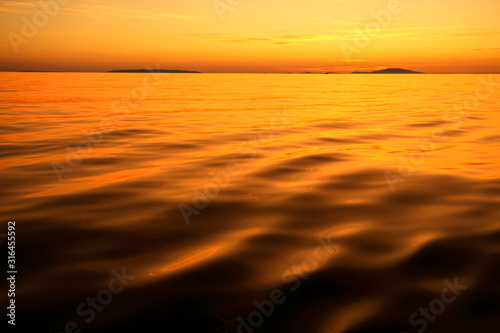 Fotografia Vivid orange color sunset with unreal colorful water surface and sky