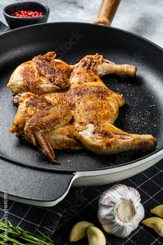 Grilled fried roast Chicken Tabaka in a pan. Gray background. Top view